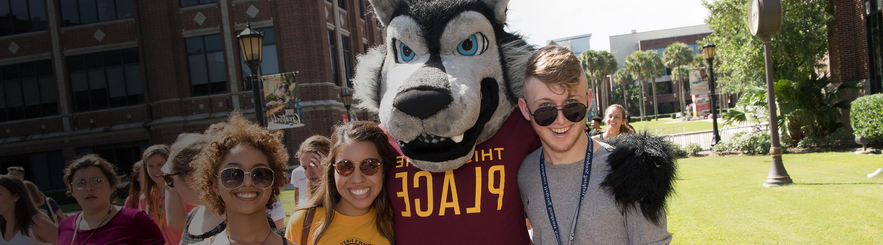 Group of smiling students with wolf mascot Havoc